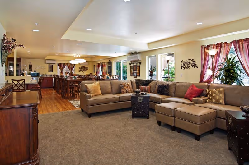Spacious lounge with a large sectional sofa, coffee tables, dining area, and plants.