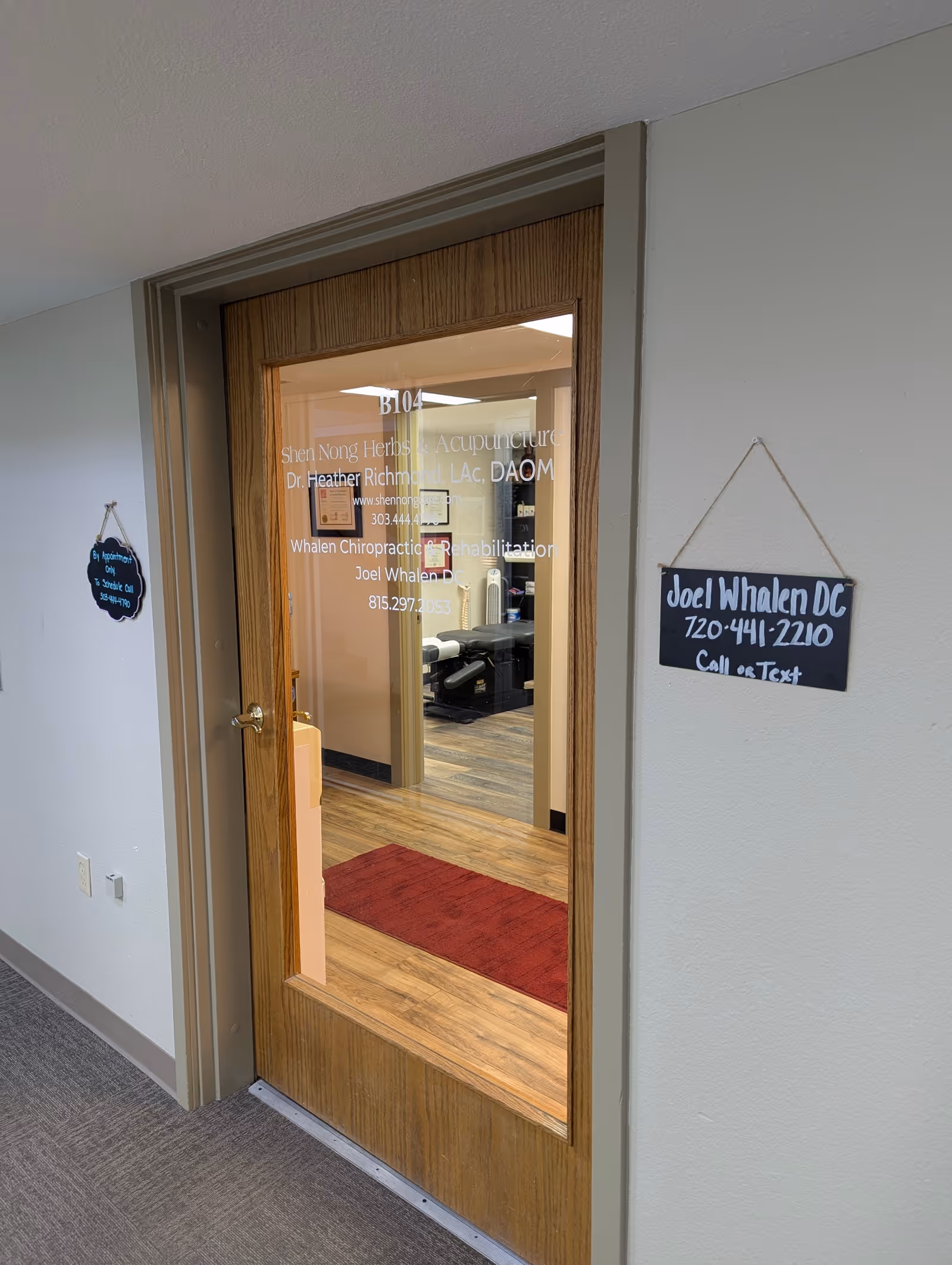 Wooden door with glass panel opens to an office area with signs and a red rug.