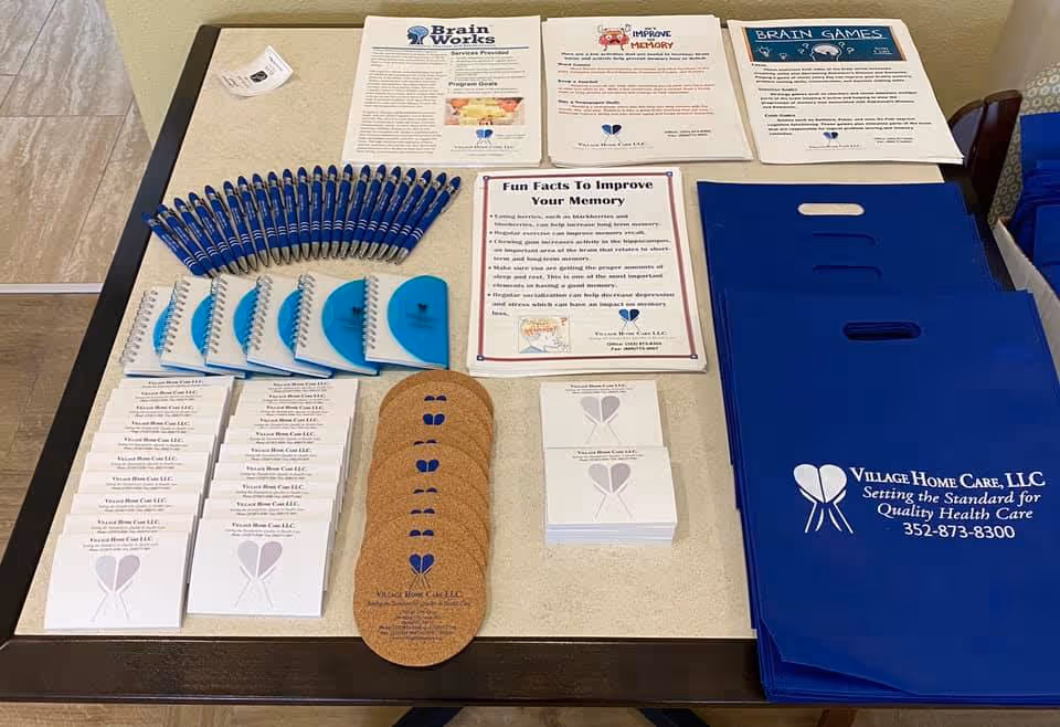 A desk with blue brochures, pens, and stacks of business cards for Village Home Care.