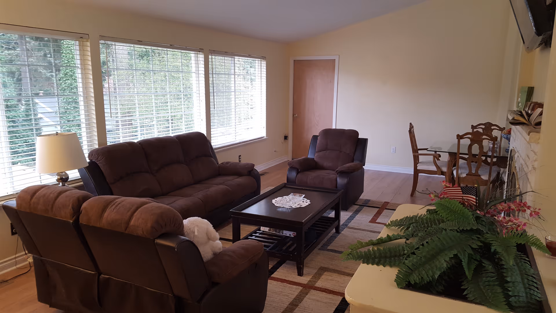 Spacious living room with brown sofas, a coffee table, and a dining area near large windows.