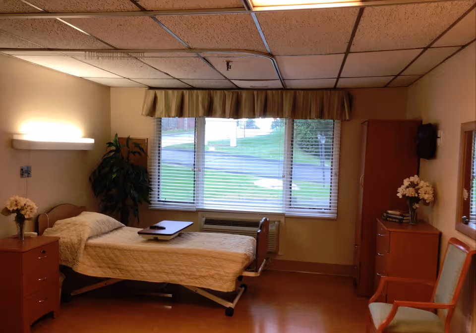 Senior living facility bedroom with a bed, dresser, and window view.