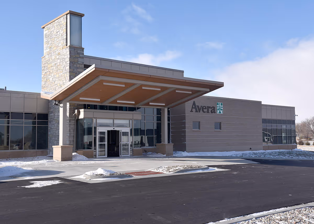 Avera building entrance with stone chimney and glass front in snow