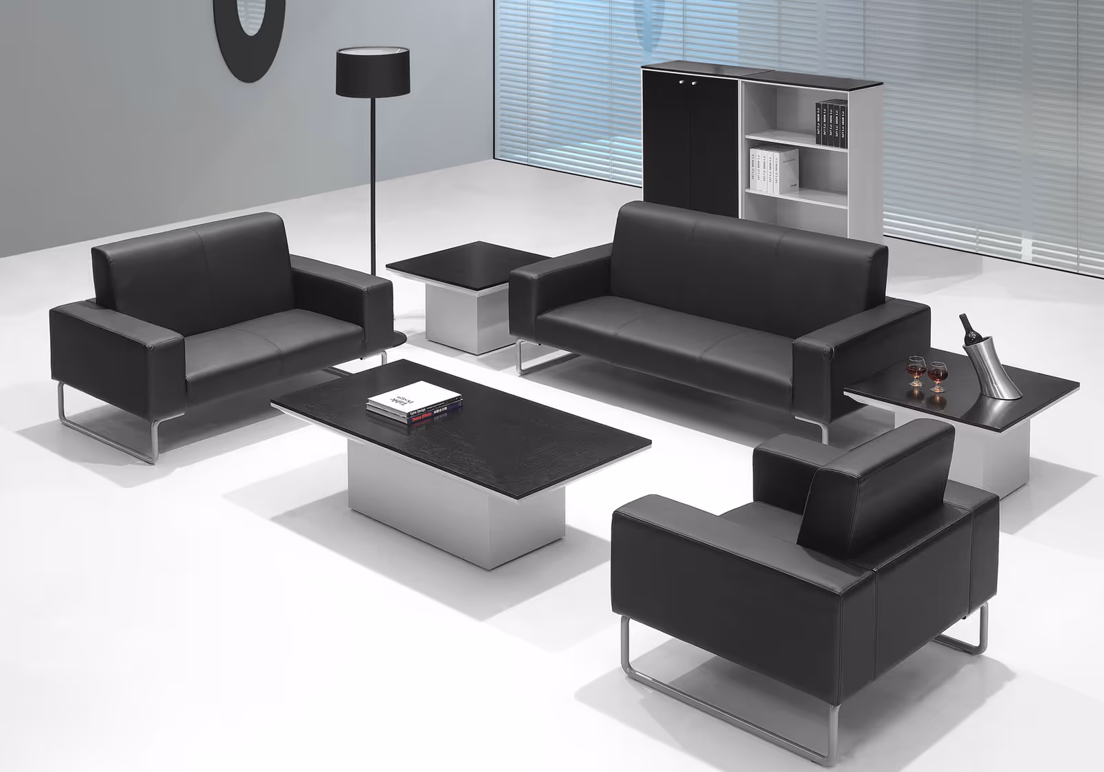 Modern lounge area with black leather seating, coffee tables, and a bookshelf.