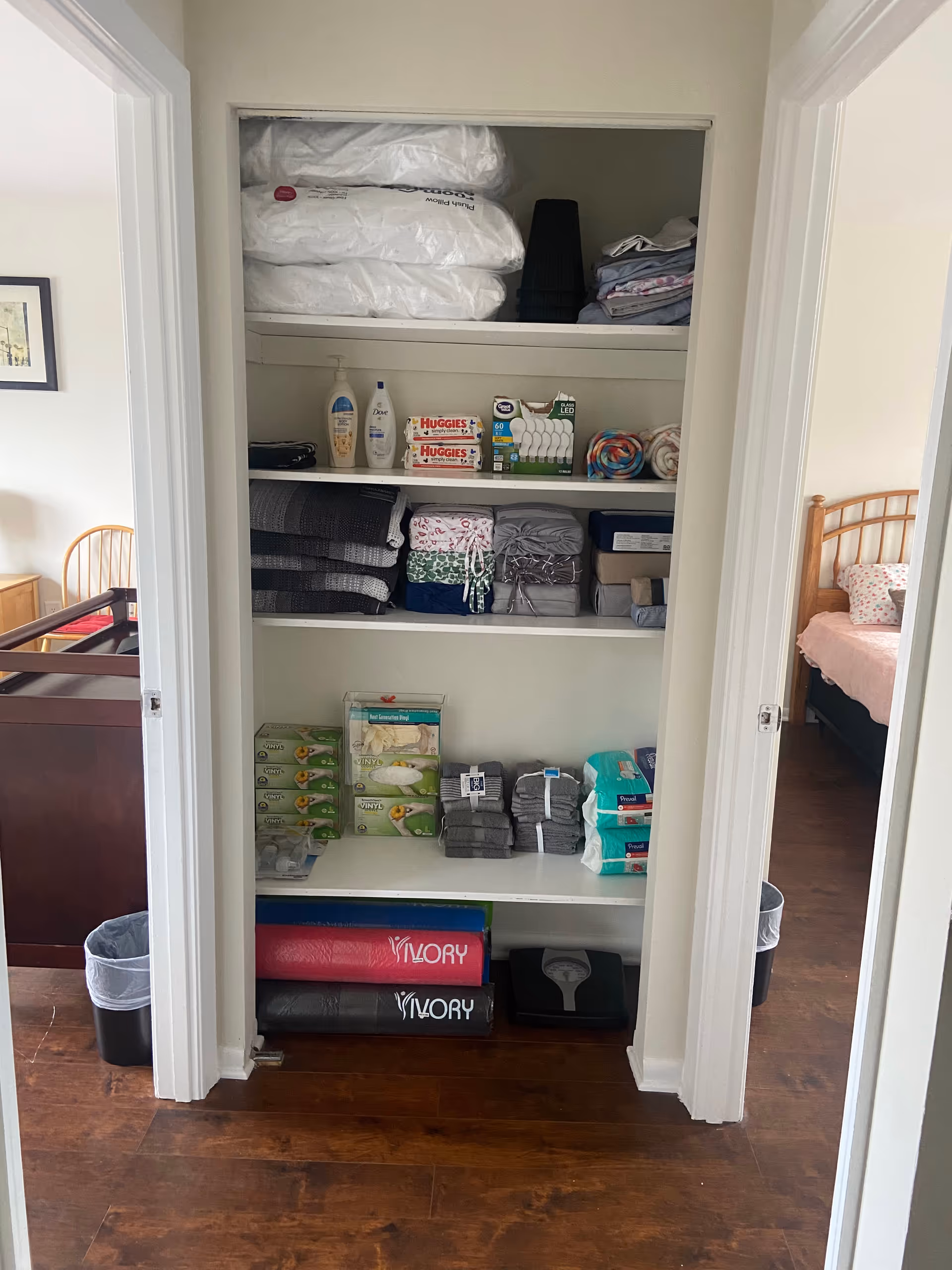 Open closet in a senior living facility storing bedding, towels, toiletries, and supplies.