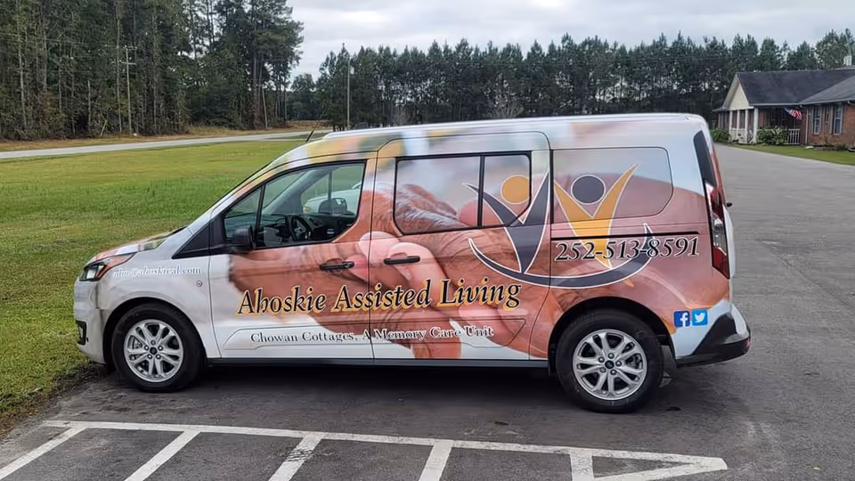 Pinewood Manor Assisted Living van parked in a lot beside a brick building.