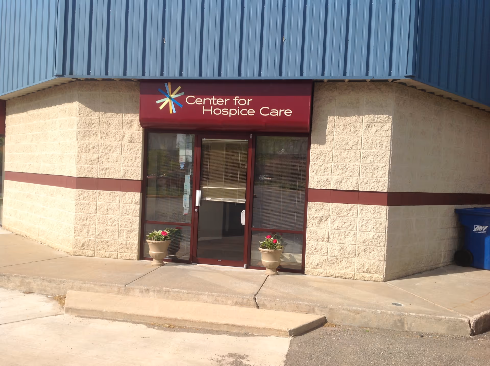 Exterior view of the Center for Hospice Care entrance with glass doors and planters.