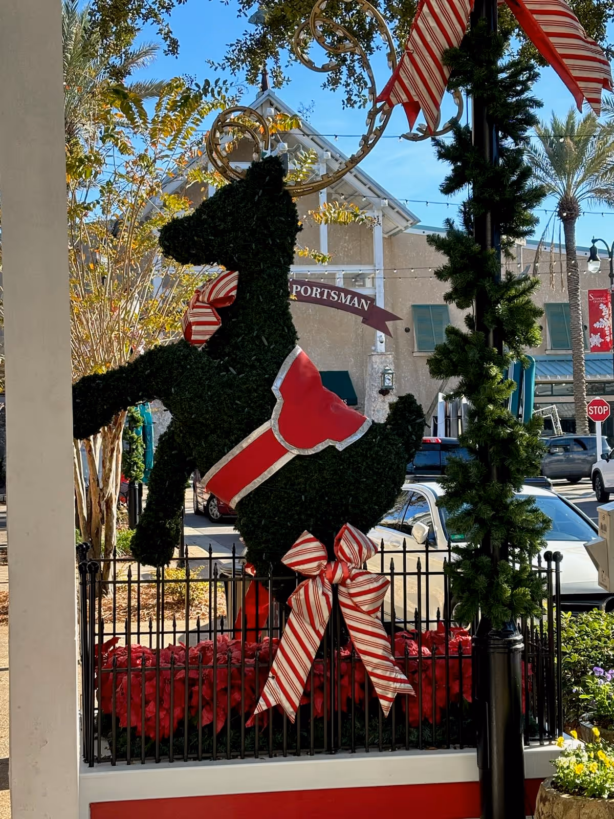 Holiday display with a large deer topiary outside a storefront.