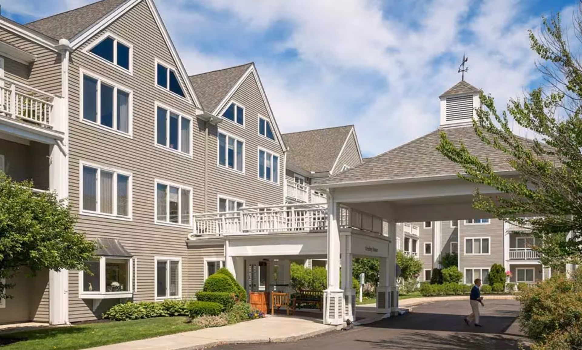 Multi-story senior living complex with beige siding, balconies, and a covered entrance.
