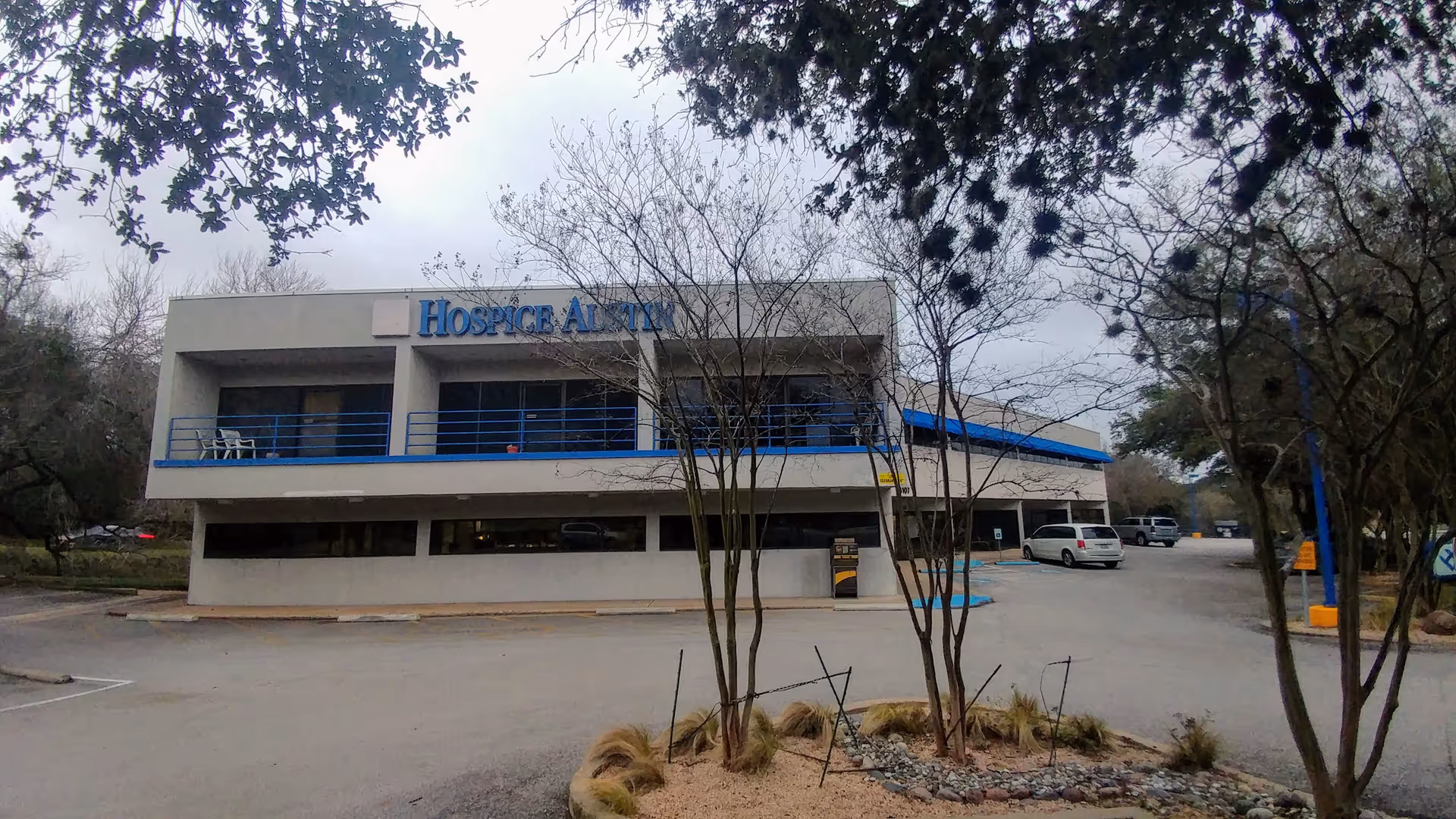 Two-story Hospice Austin building exterior with blue accents and surrounding trees.