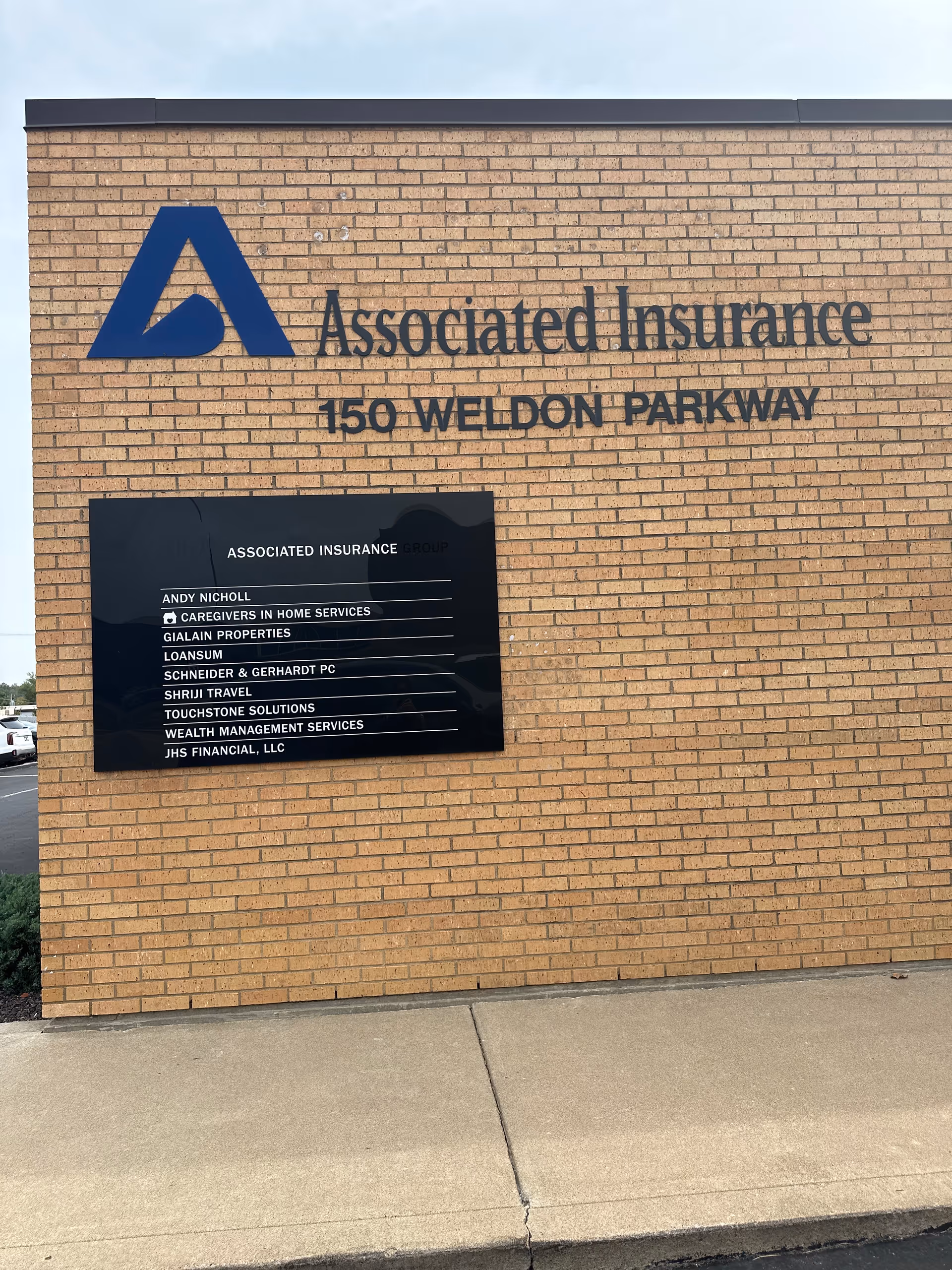 Brick exterior wall with large Associated Insurance sign and directory plaque.