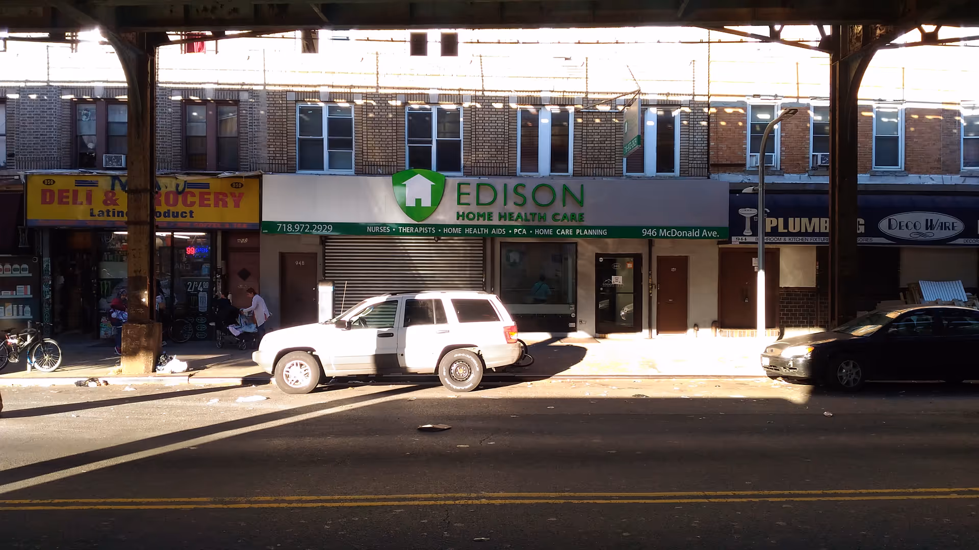 Urban storefronts along a street with Edison Home Health Care signage and a parked SUV.