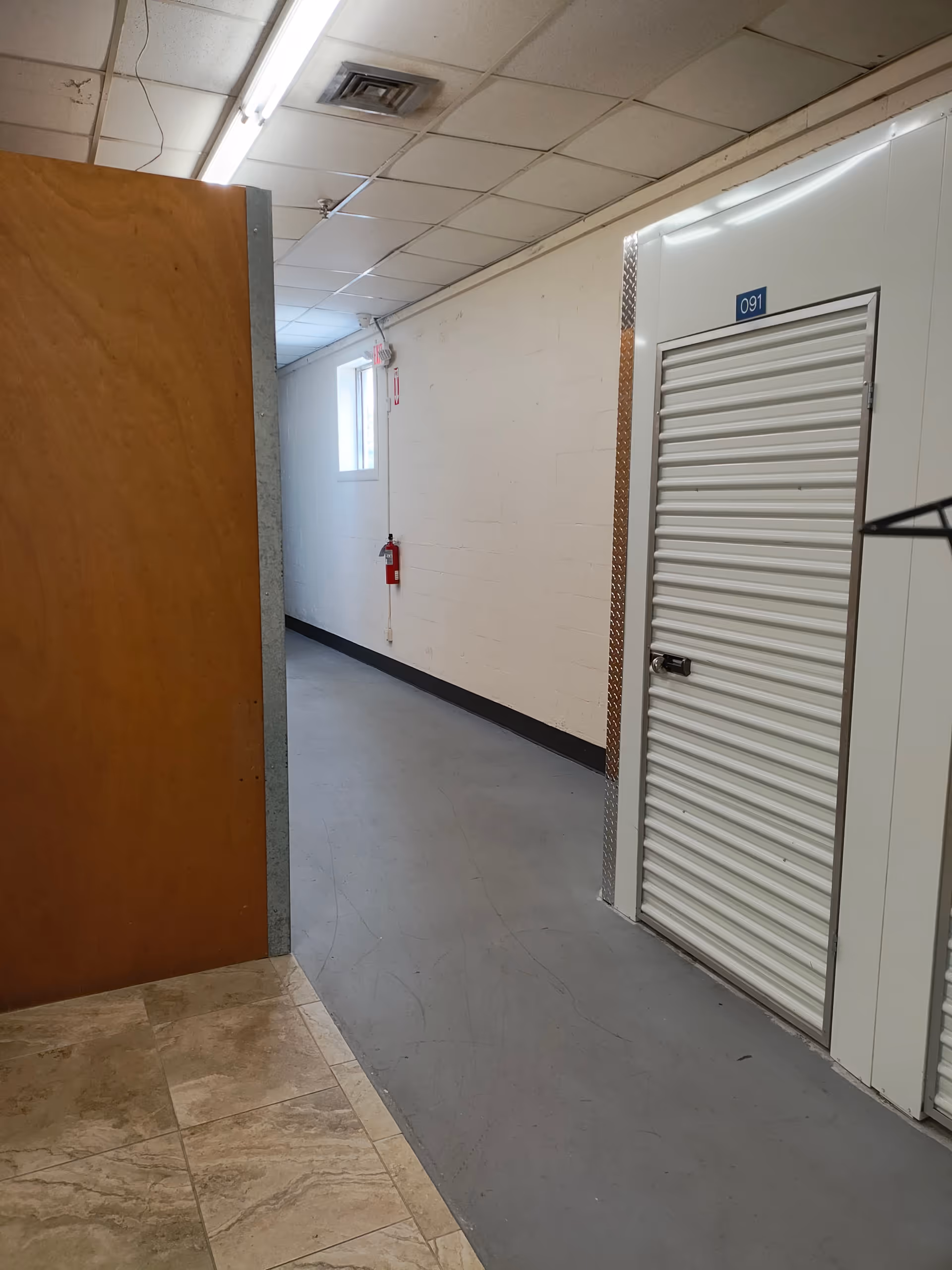 Interior corridor in a senior living facility with doors and a fire extinguisher.