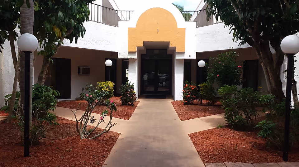 Exterior view of Vick Street Manor entrance with walkway and landscaped courtyard.