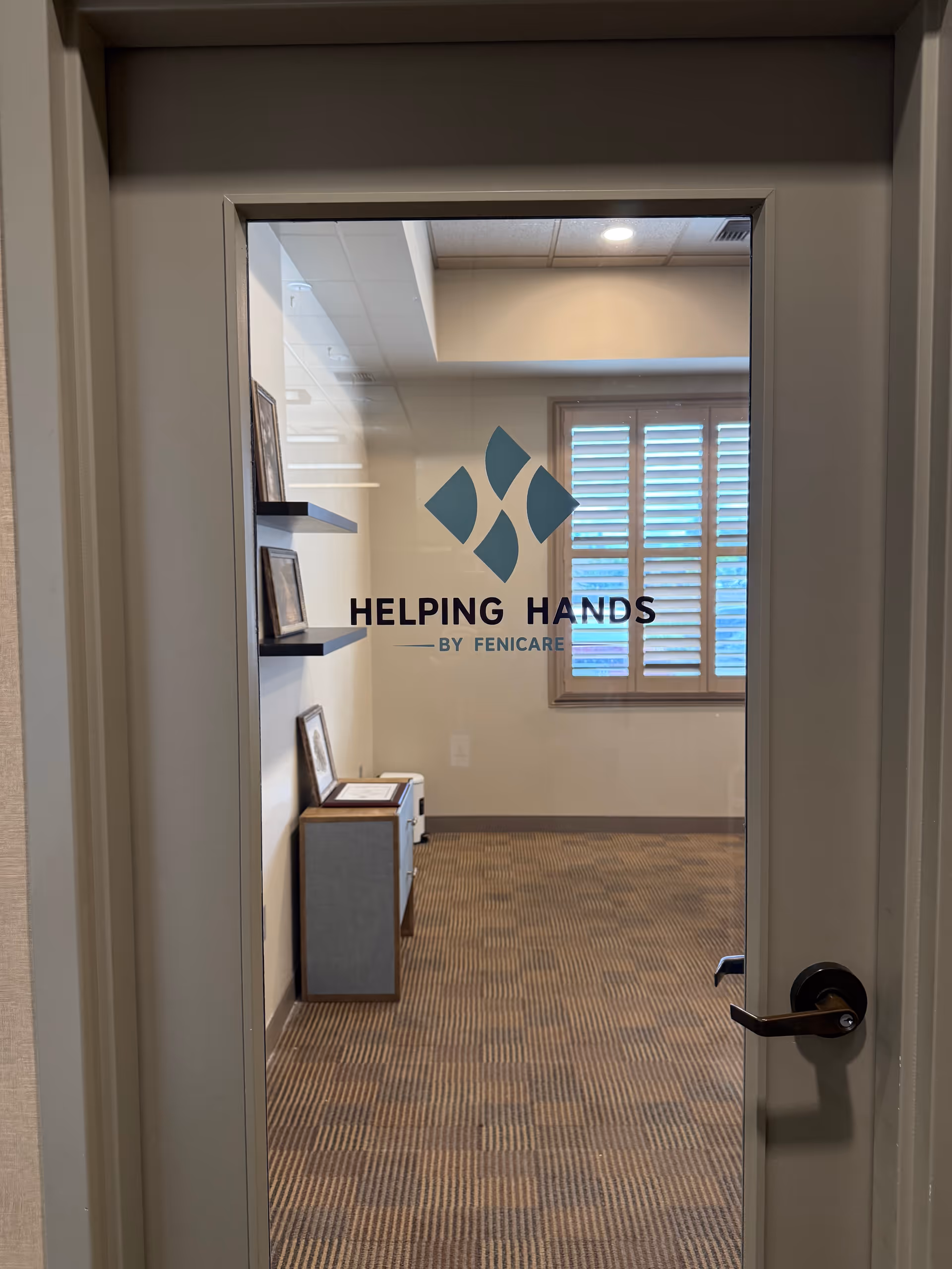 Interior doorway features Helping Hands by Fenicare branding on glass, with a carpeted hallway.