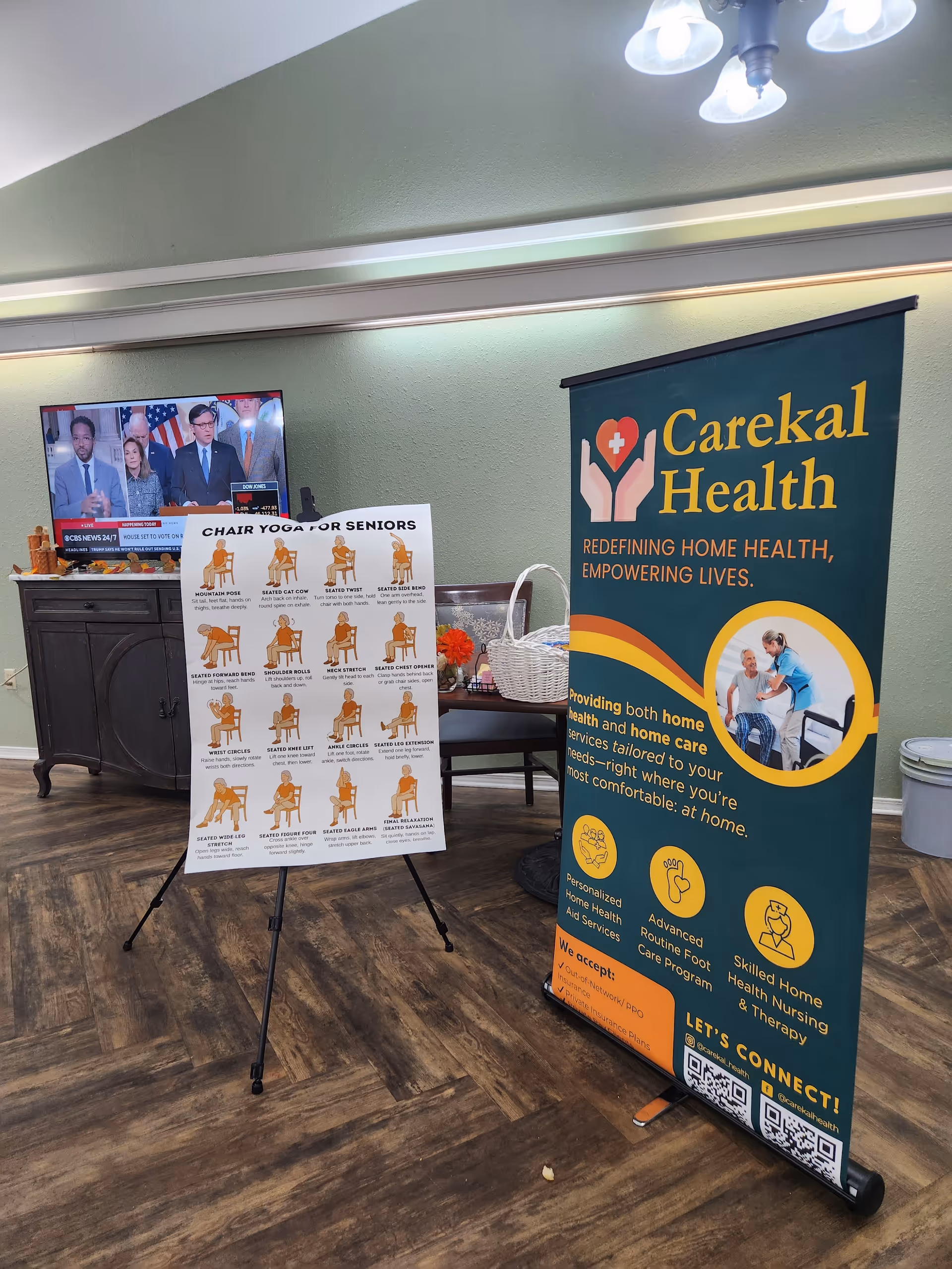 Indoor facility lobby with Carekal Health banner, chair yoga poster, and TV on a cabinet.