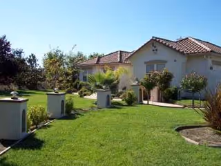 Front yard of a senior living facility with a cream building and manicured lawn.
