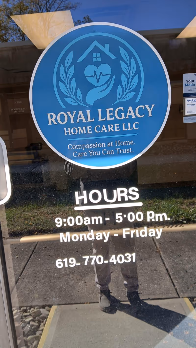 Round blue Royal Legacy Home Care logo on glass door with hours and phone number.