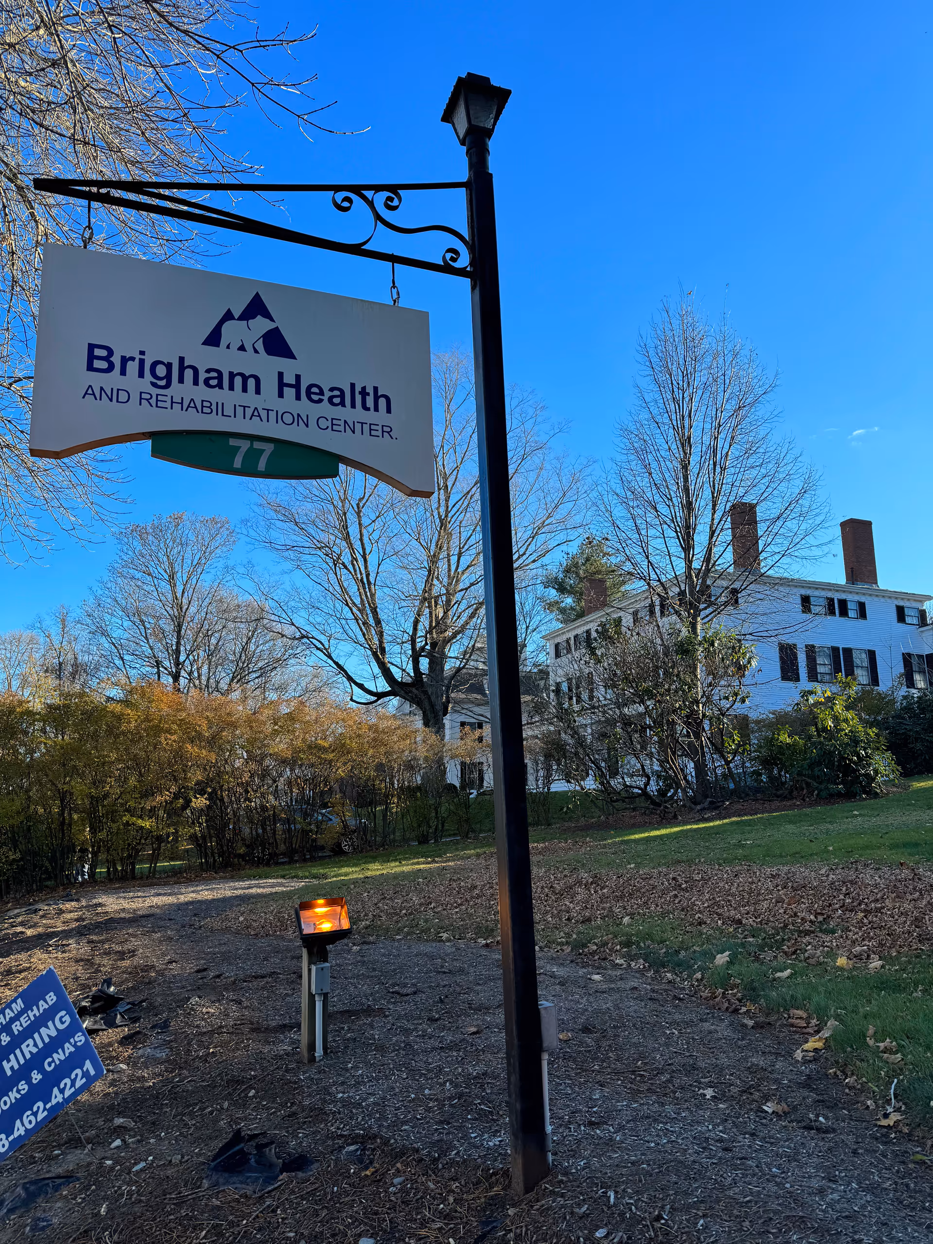 Blue sky above Brigham Health and Rehabilitation Center sign with building in background.