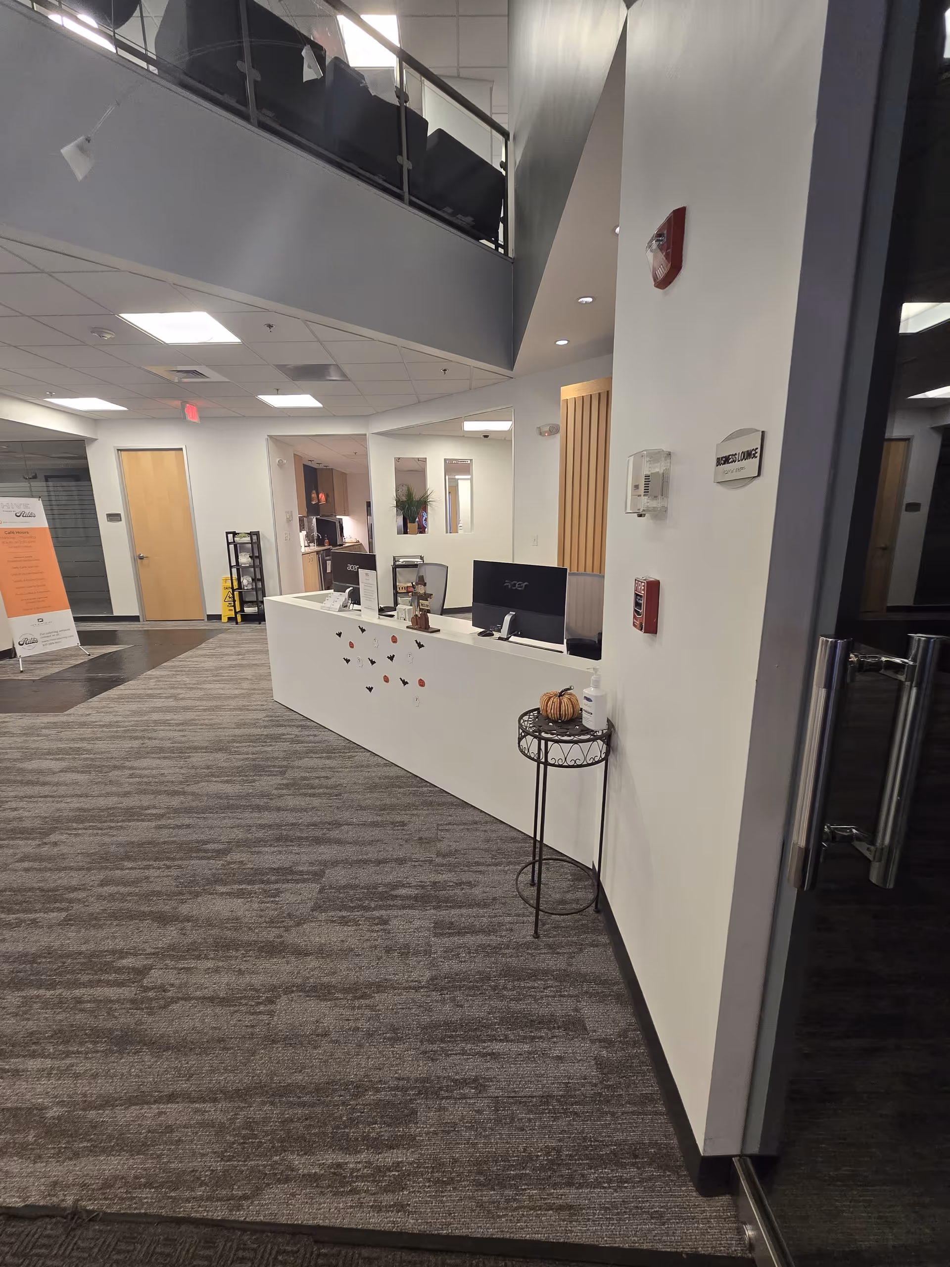 Modern reception area with white desk, computers, and hallway in a senior living lobby.