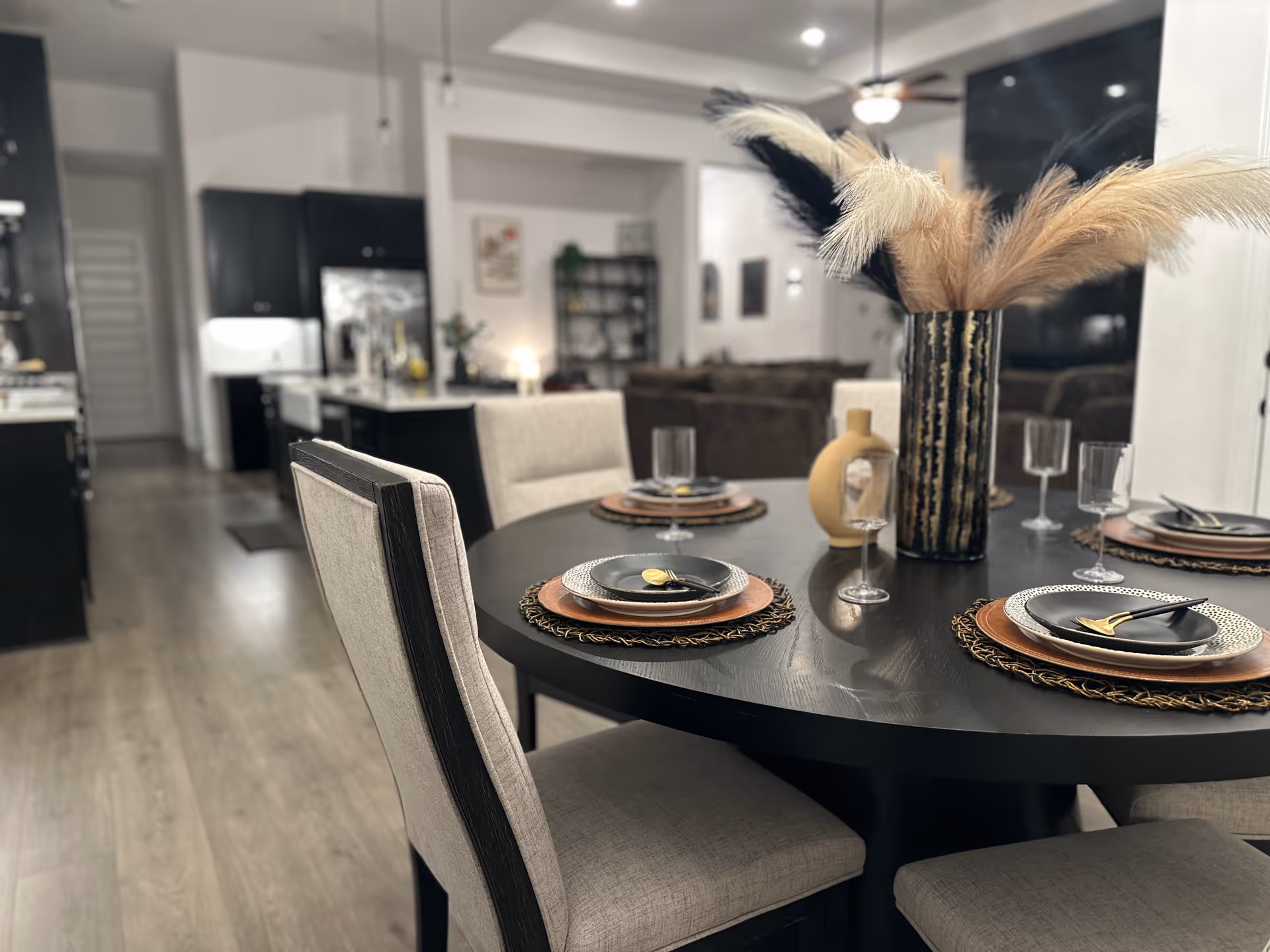 Modern dining room with a round table, place settings, and decorative centerpiece.