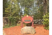 Outdoor scene showing Alpine Nursing Home sign on rock amid trees