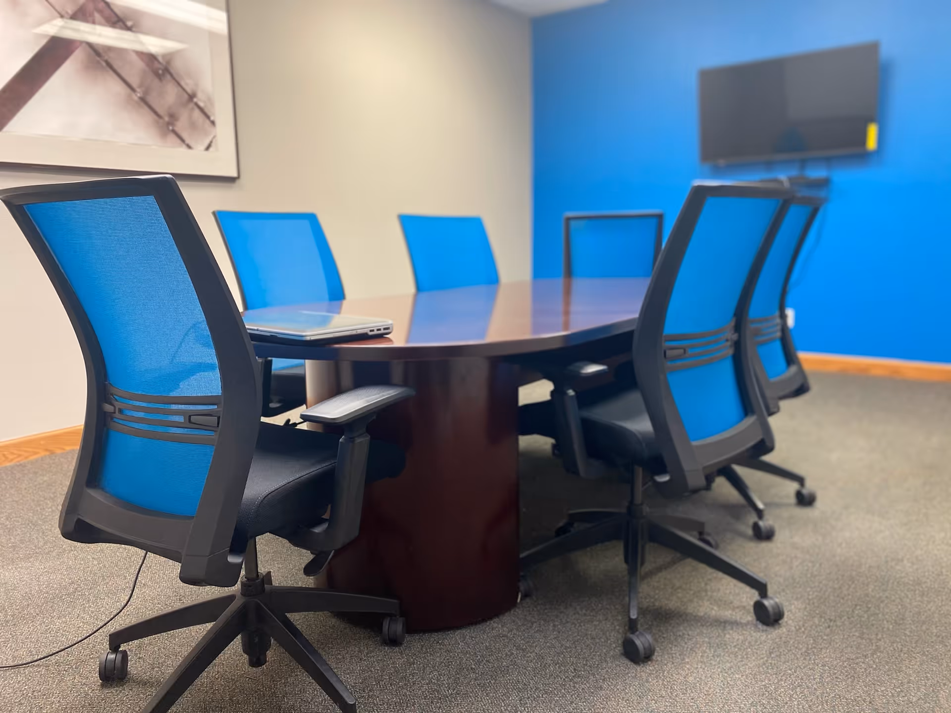Blue walled conference room with a round table and blue chairs.