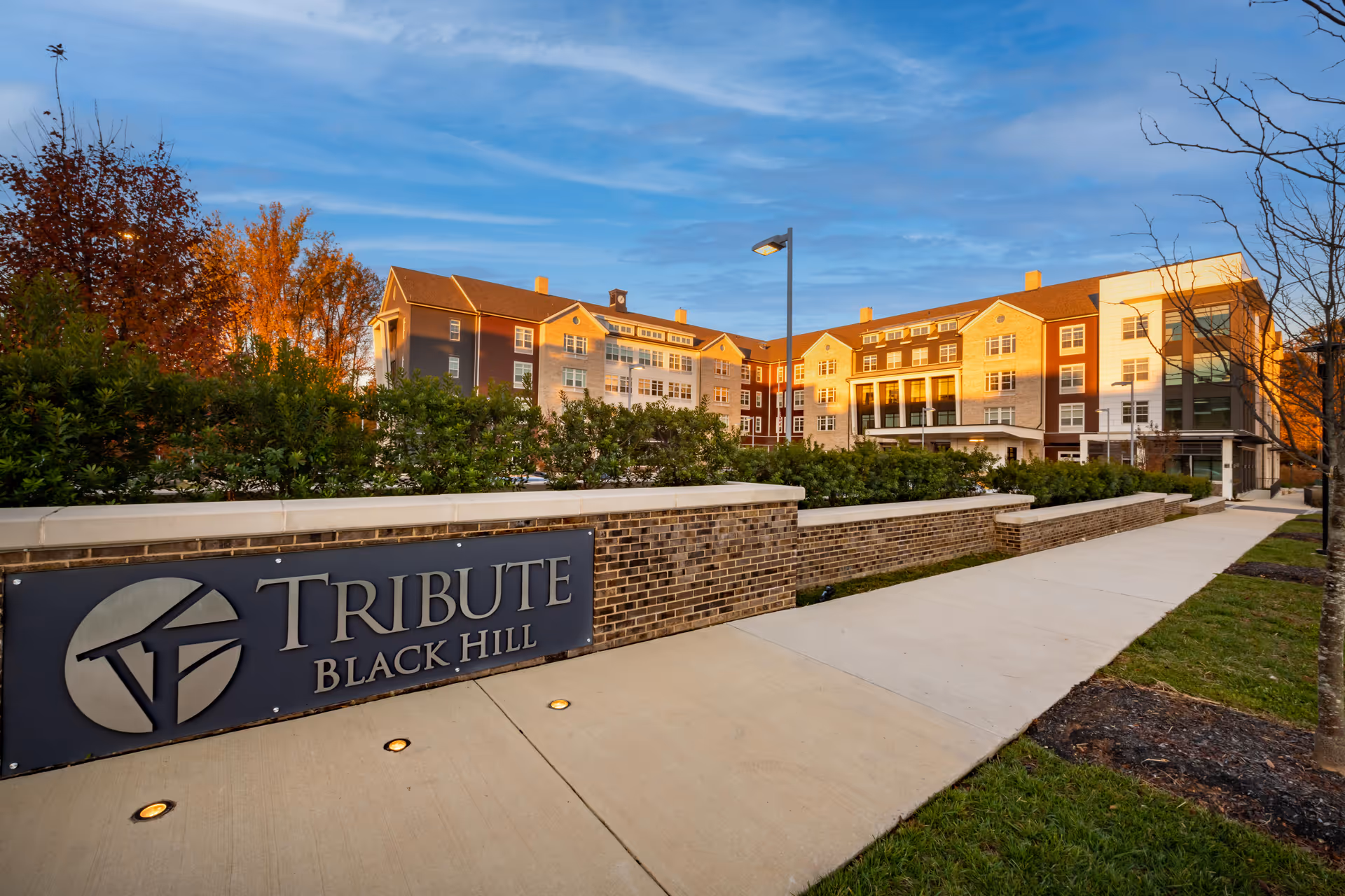 Front entrance and facade of the Tribute at Black Hill senior living building with a sign in the foreground.