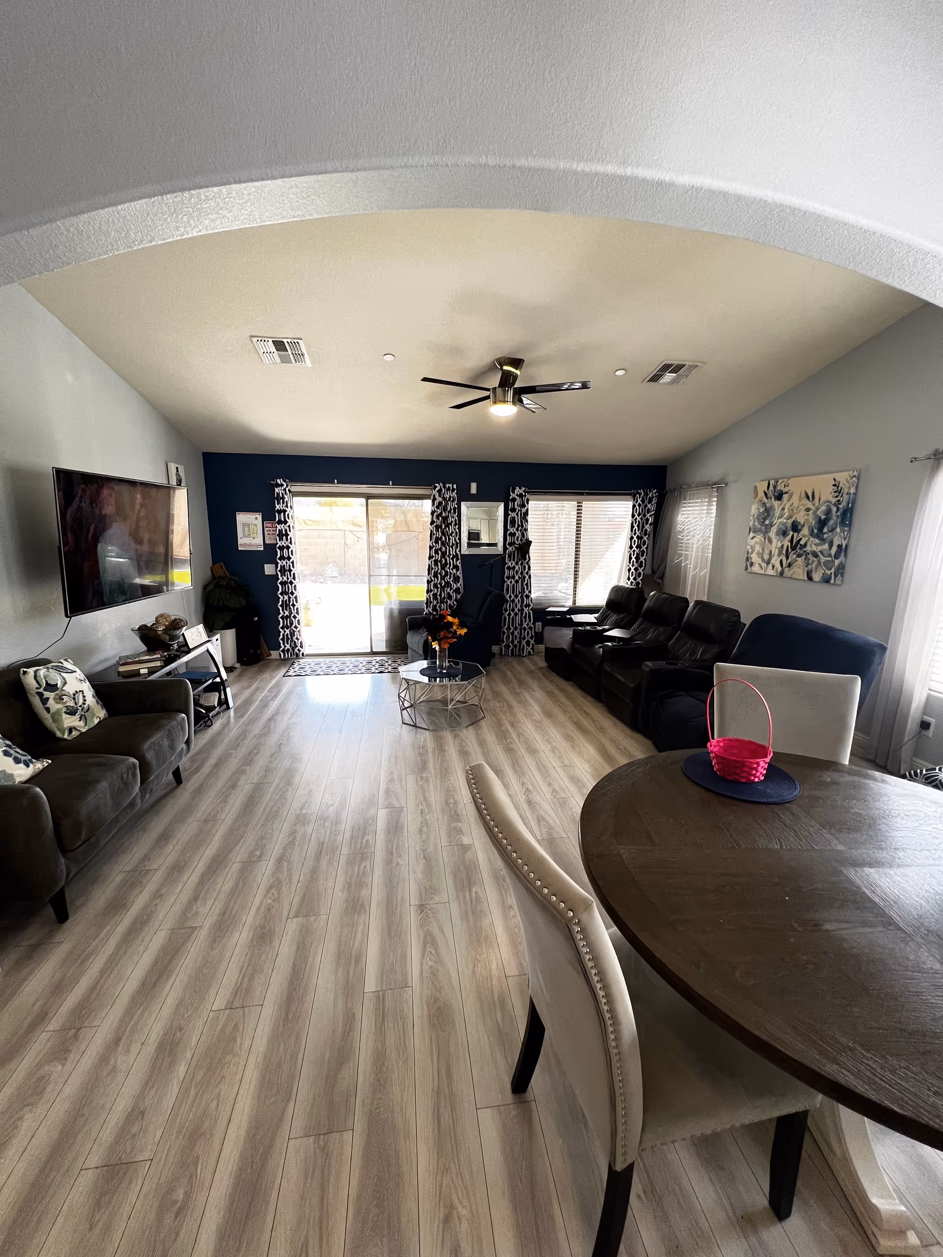 Spacious living room with sofas, TV, dining table, and sliding glass doors.