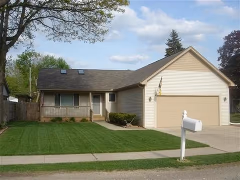 Front view of a single-story house with a green lawn and driveway.