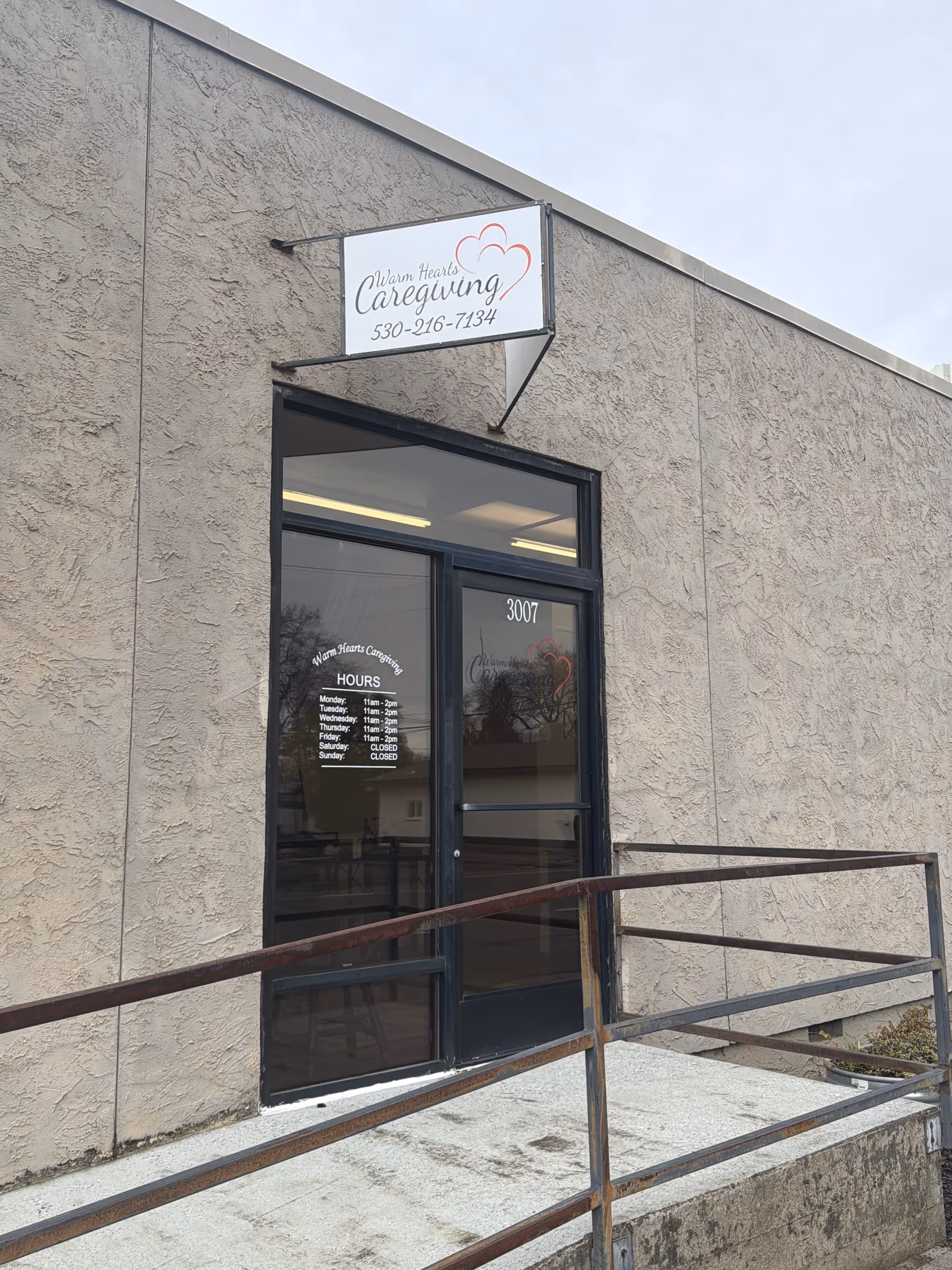 Exterior view of Warm Hearts Caregiving entrance with sign and railing.