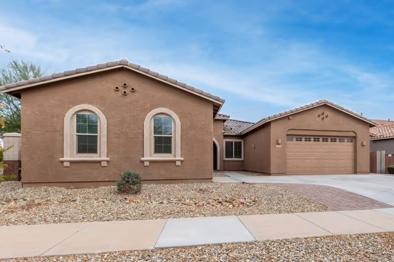 Brown stucco senior living facility exterior with a two-car garage and desert landscaping.