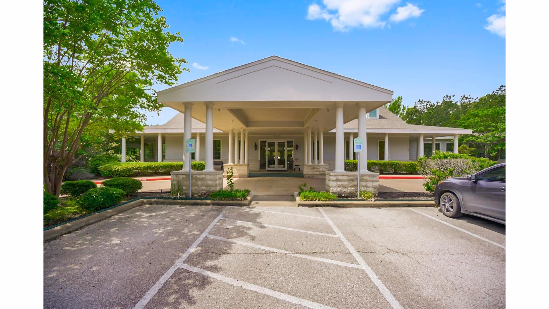 Front entrance of Sundale Senior Living building with a covered drop-off and parking.