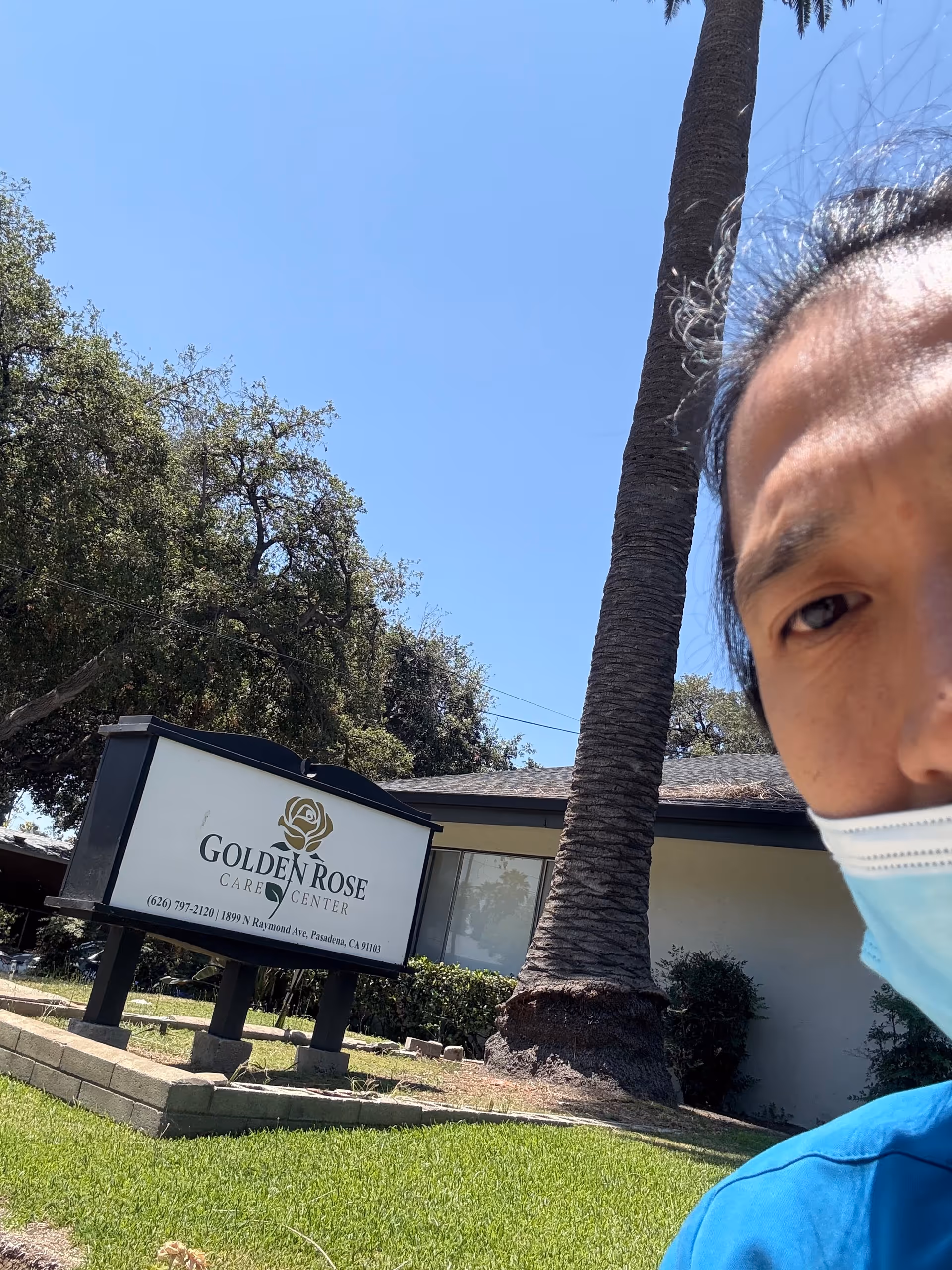 Exterior view of Golden Rose Care Center sign with a masked person at the edge.