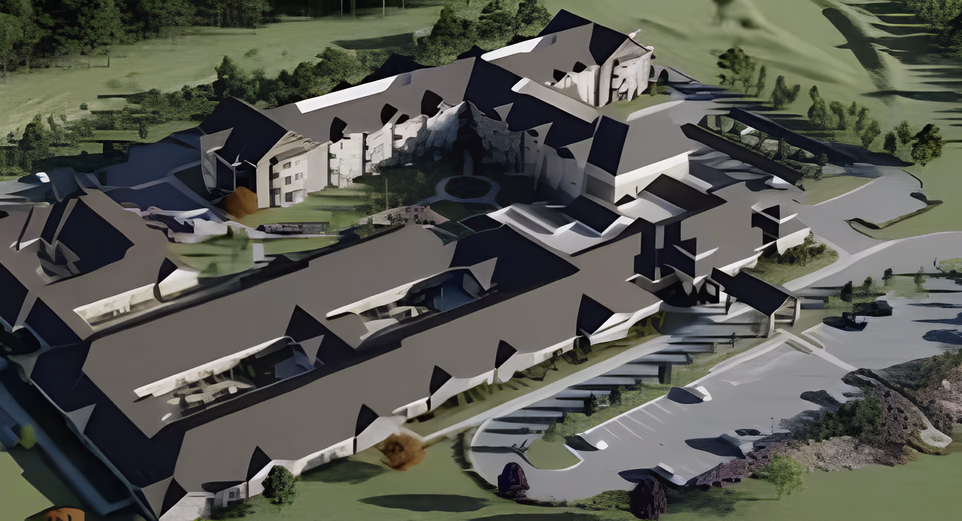 Aerial view of a senior living facility showing multiple connected buildings with dark roofs, surrounded by green lawns, trees, and a parking lot.