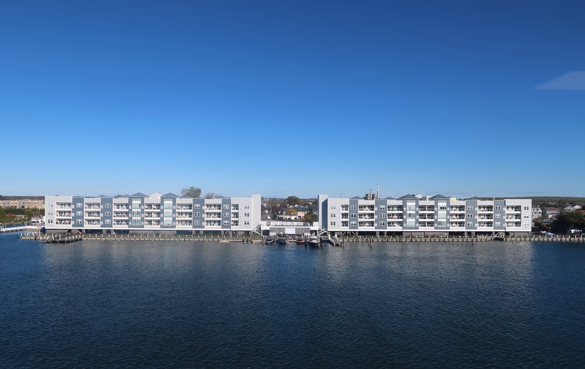 Long, modern, multi-story building along a waterfront with balconies.