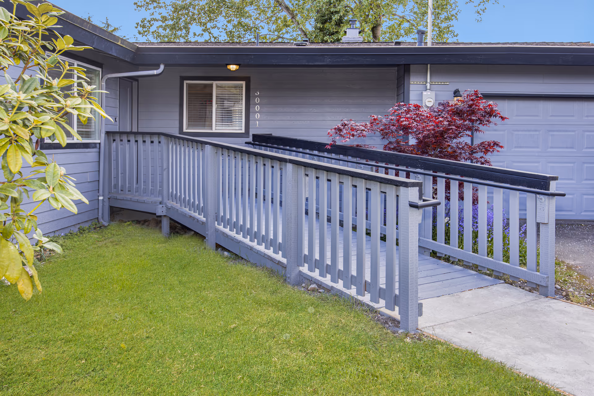Ramped walkway leads to a gray, single-story facility with a front door.