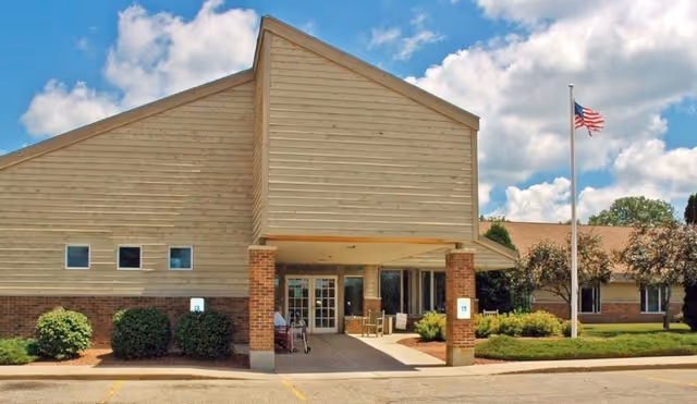 Front exterior of Wellington Meadows senior living facility with entrance and flag