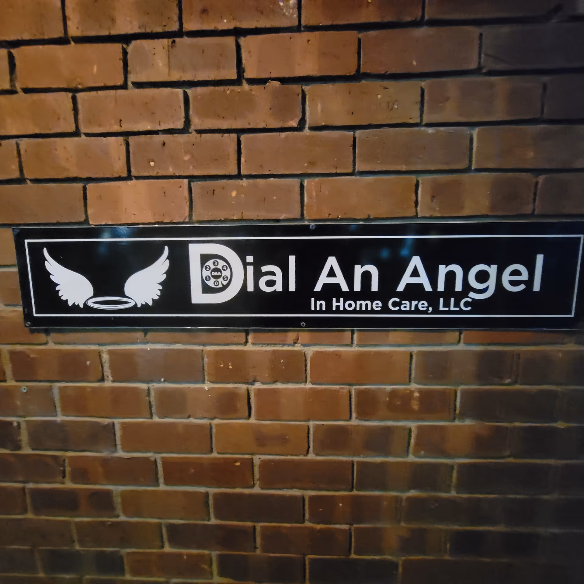 Brick wall with a sign reading Dial An Angel In Home Care, LLC.