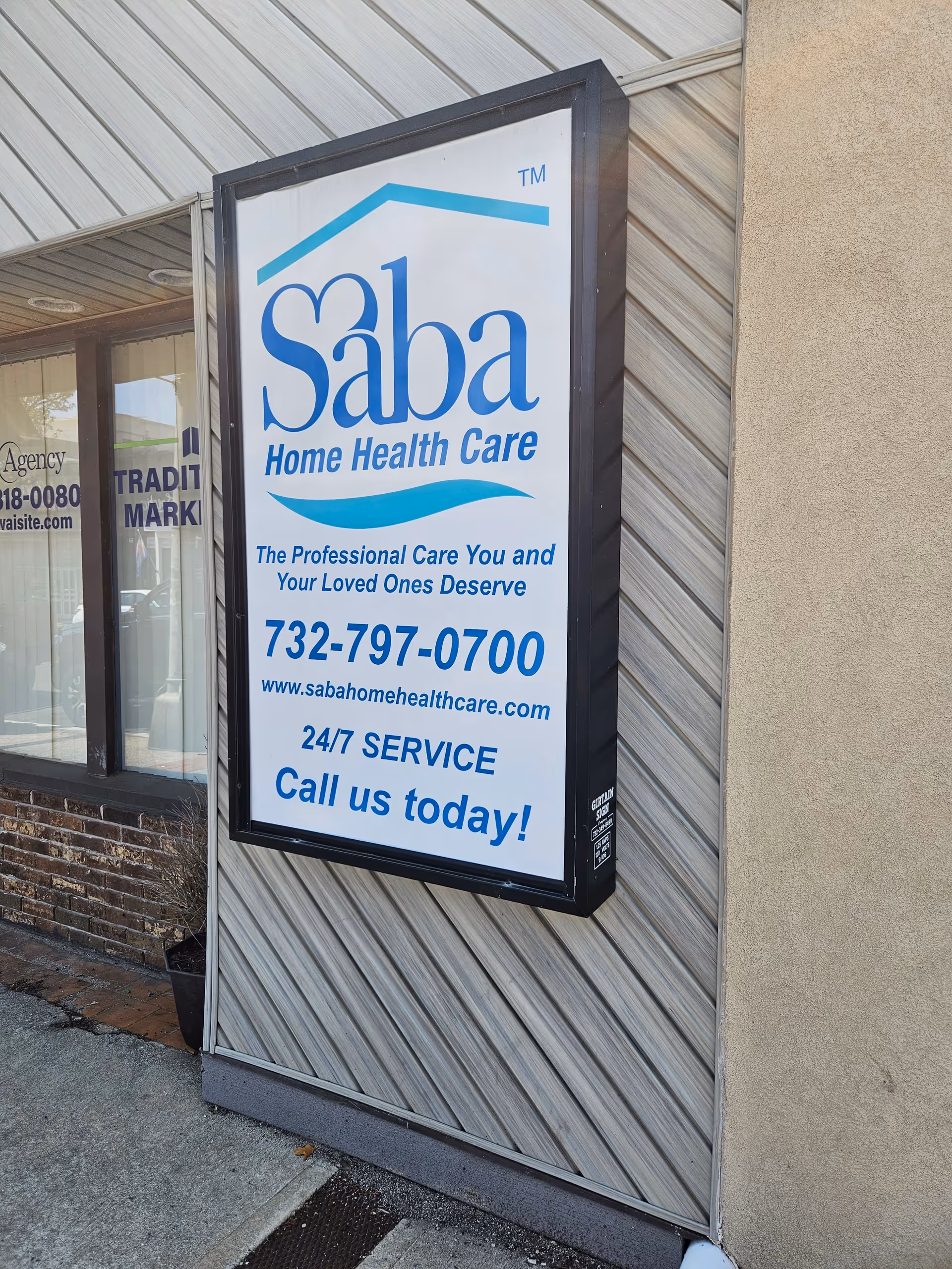 Vertical sign on a building reads Saba Home Health Care with phone number and URL.