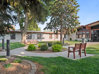 Outdoor courtyard at Good Samaritan Society - Villa with benches, trees, and landscaped grounds.