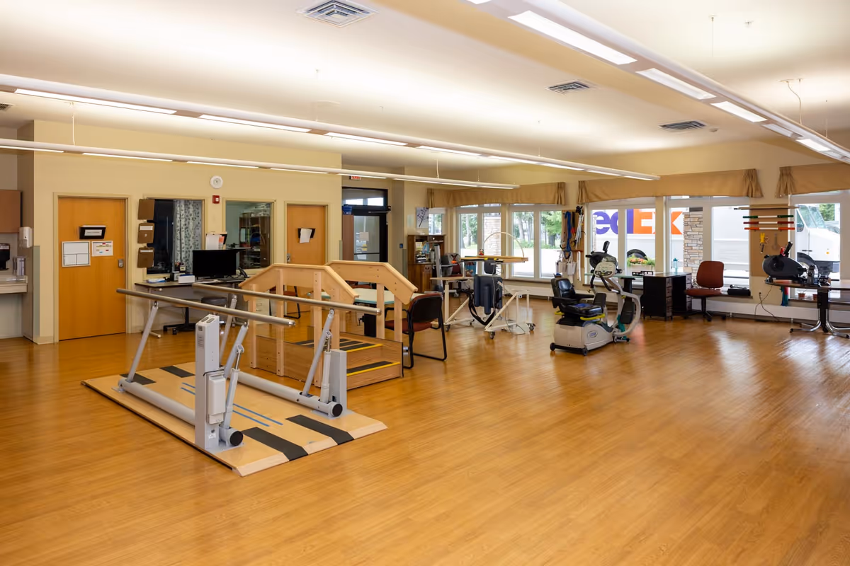 Spacious rehabilitation gym at Benedictine Living Community-Wausau with exercise equipment and wooden floors.