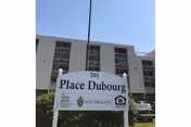 Front view of Place Du Bourg senior living facility with signage and building in background.