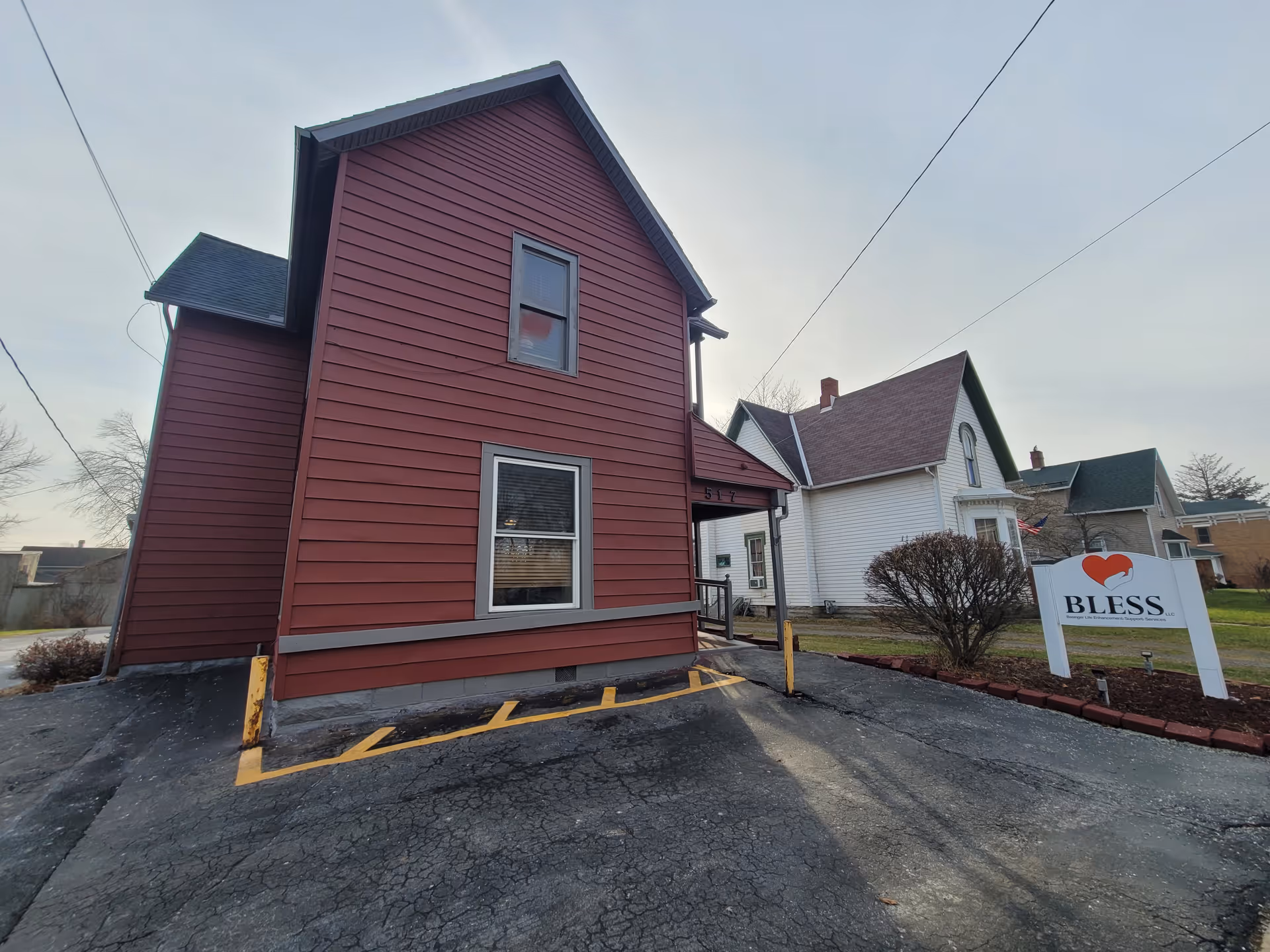 Red two-story building with a Bless LLC sign and a small parking lot.