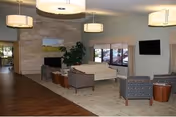 Spacious lounge area with sofas, chairs, a fireplace, and a wall-mounted TV.