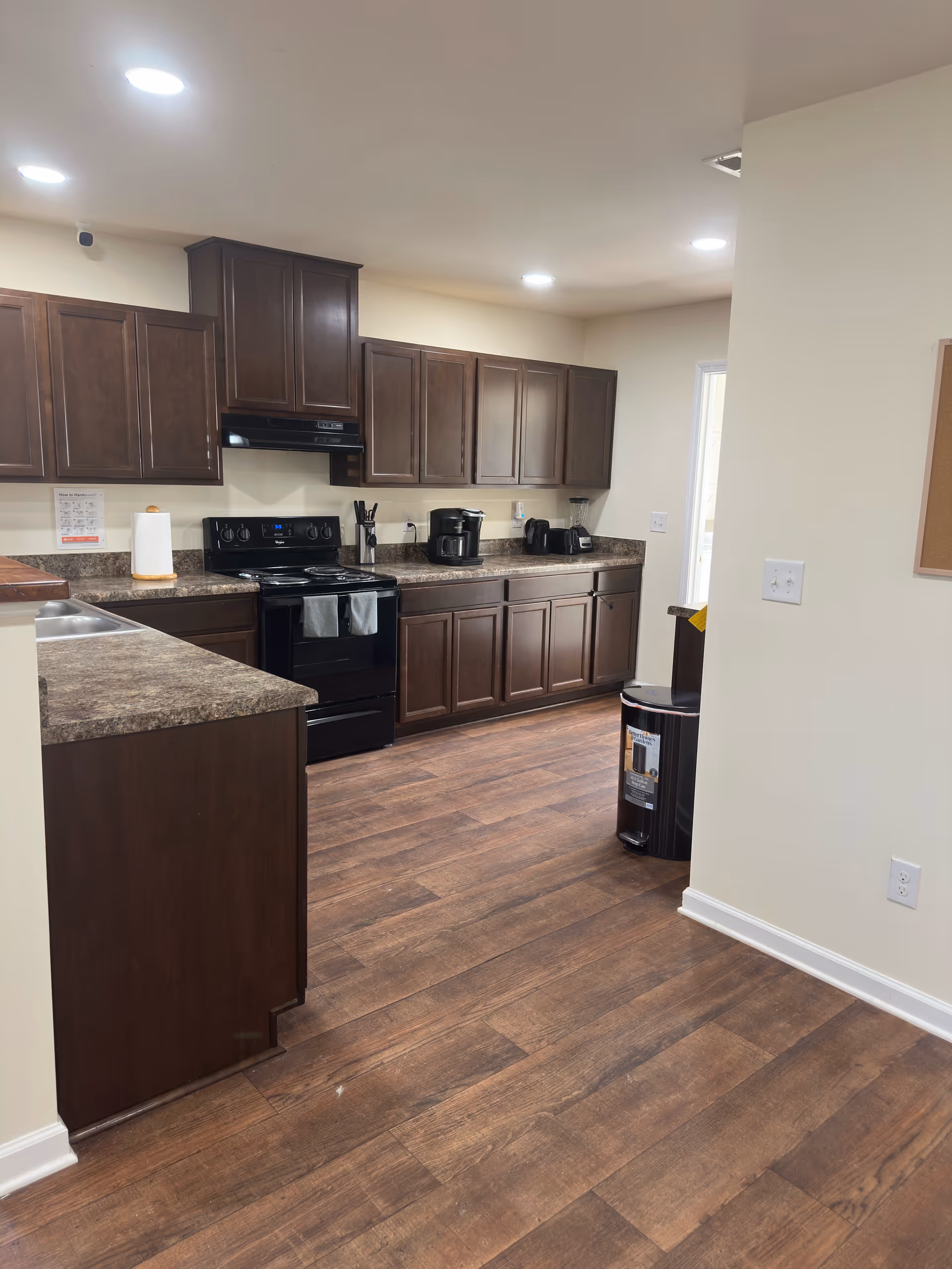 A spacious kitchen with dark wood cabinets, granite countertops, and appliances along the wall.