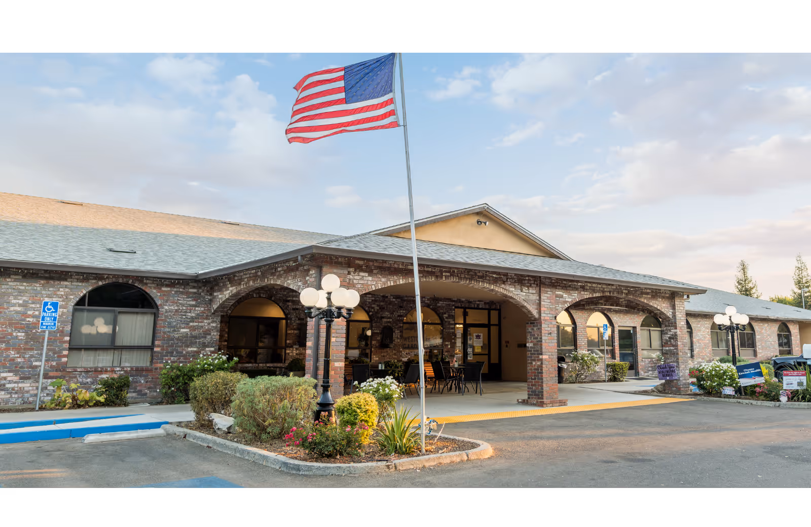 Westgate Gardens Care Center exterior with brick arches, front entrance, and an American flag.