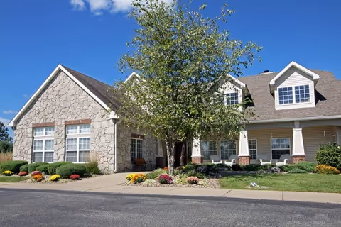 Exterior view of Riverbend senior living building with stone facade, landscaping, and a tree.