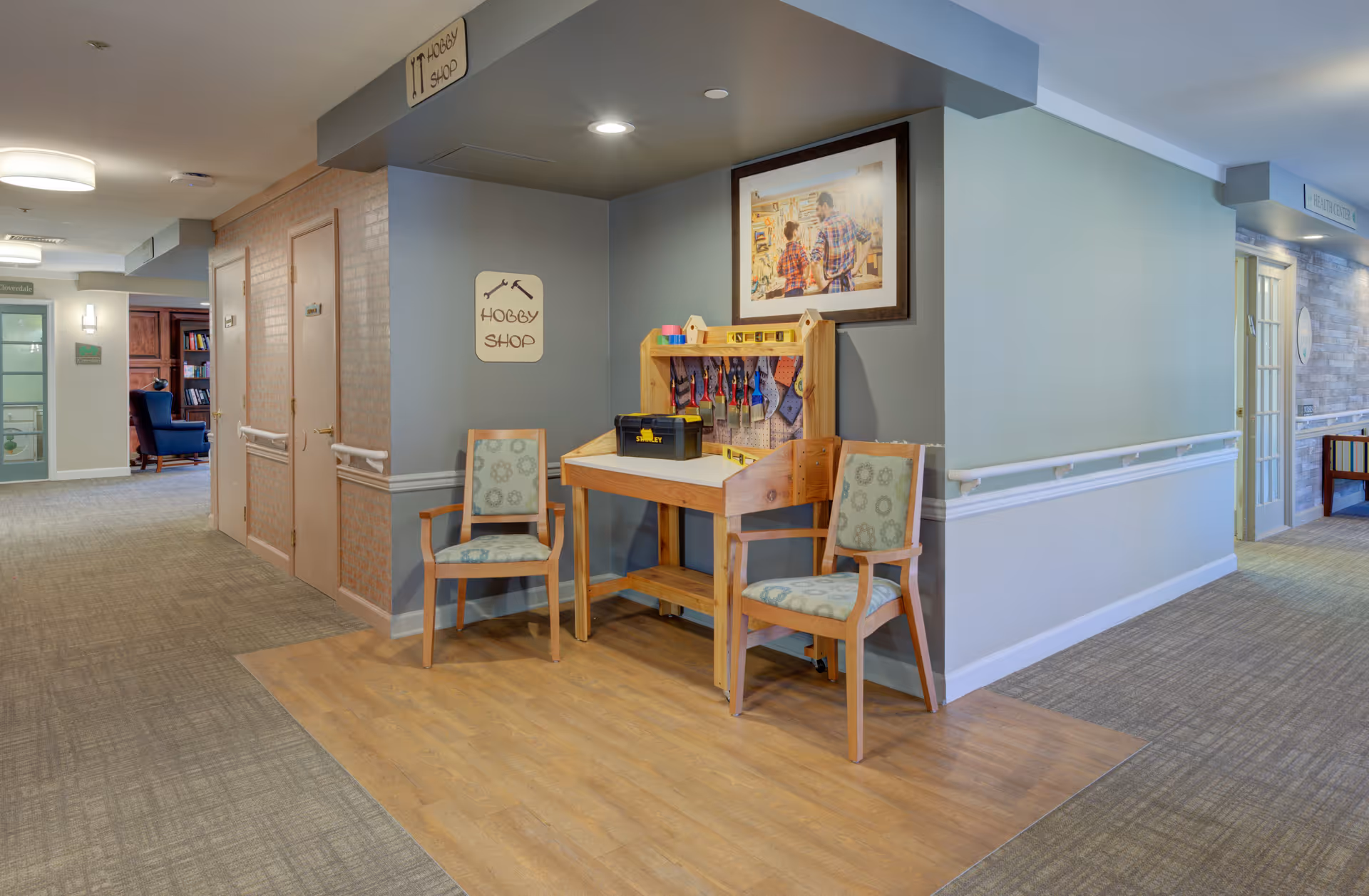 Interior hallway of Arden Courts West Orange with a hobby shop desk and two chairs.