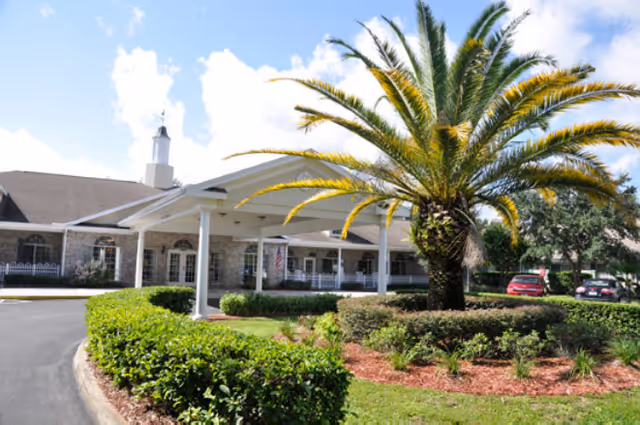 Exterior view of The Colonnade at Carrollwood entrance with a covered portico and palm tree.