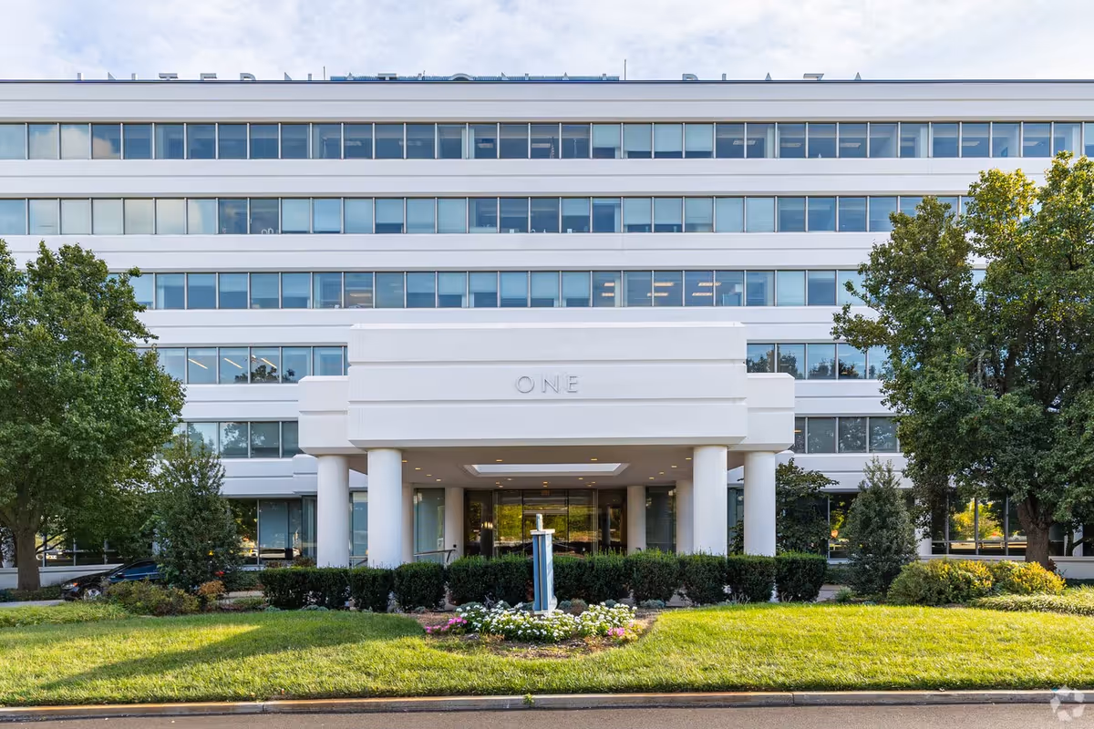 Modern white multi-story building with a covered entrance and manicured landscaping.